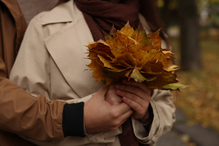 Happy young couple with dry leaves in autumn park, closeupの写真素材