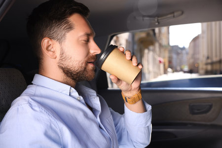 To-go drink. Handsome man drinking coffee in car, space for textの写真素材