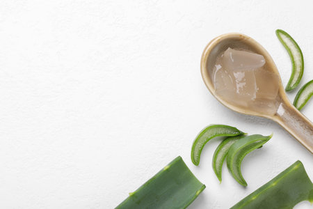 Aloe vera gel in spoon and slices of plant on white background, flat lay. Space for textの写真素材