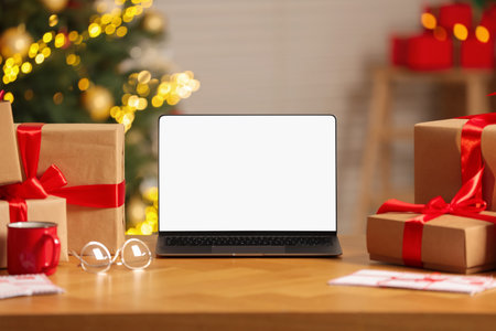 Laptop with blank screen, Christmas gifts and letters on table at homeの写真素材