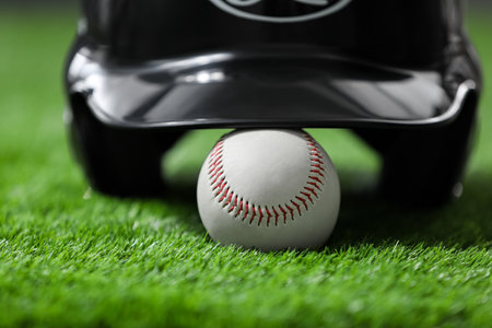 Batting helmet and baseball ball on green grass, closeupの写真素材