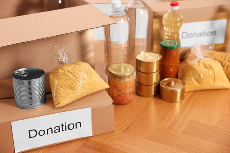 Volunteering. Different food products and cardboard boxes on tableの写真素材