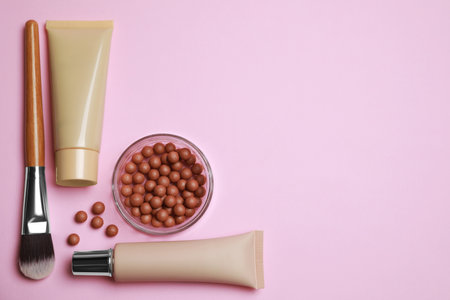 Face powder balls and other decorative cosmetic products on pink background, flat lay. Space for textの写真素材