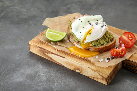 Delicious sandwich with guacamole, shrimps and fried egg on gray table, closeupの写真素材