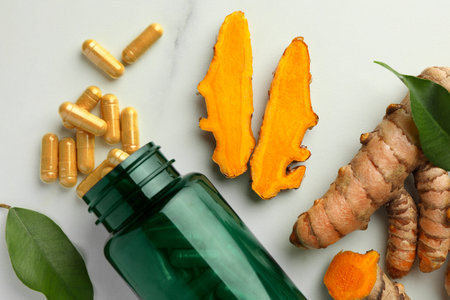 Turmeric roots, pills and bottle on white marble table, flat layの写真素材