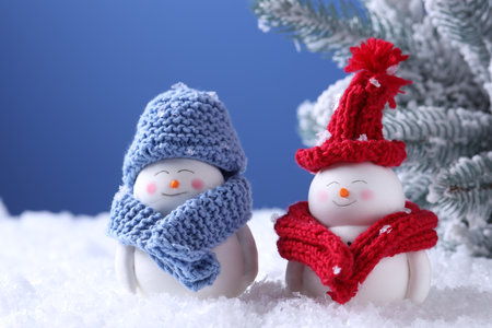 Cute decorative snowmen and fir tree on artificial snow against light blue background, closeupの写真素材