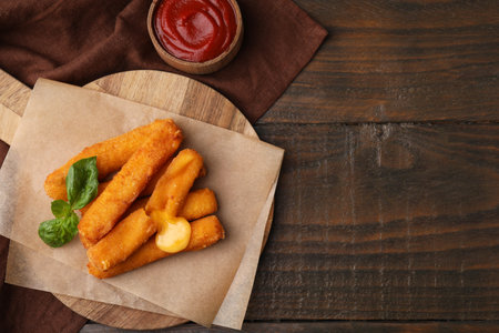 Tasty fried mozzarella sticks and tomato sauce on wooden table, flat lay. Space for textの写真素材