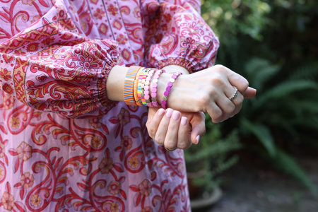 Woman wearing many stylish bracelets outdoors, closeup