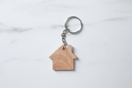 Wooden keychain in shape of house on marble table, top viewの写真素材