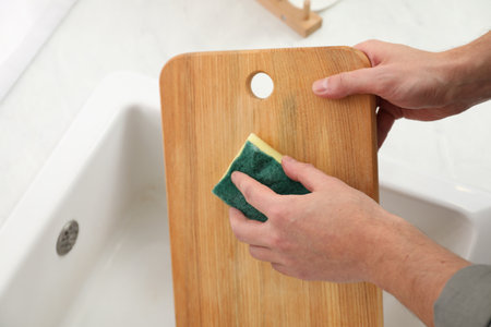 Man washing wooden cutting board in kitchen, closeupの写真素材