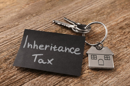 Inheritance Tax. Card and keys with key chain in shape of house on wooden table, closeupの写真素材