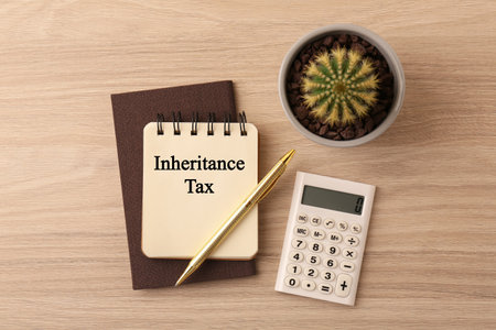 Notepad with phrase Inheritance Tax, cactus and calculator on wooden table, flat layの写真素材