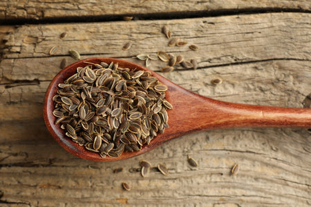 Spoon of dry dill seeds on wooden table, top viewの写真素材