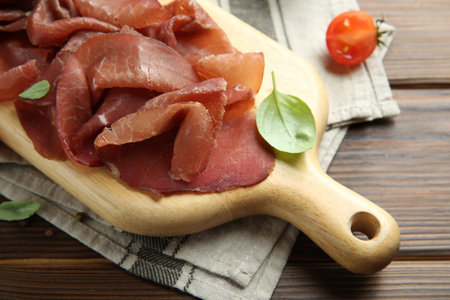 Board with delicious bresaola on wooden table, closeupの写真素材