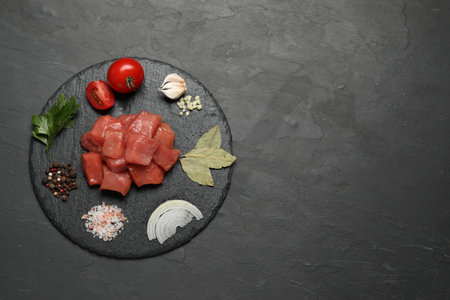 Raw beef meat and different ingredients for cooking delicious goulash on black table, top view. Space for textの写真素材