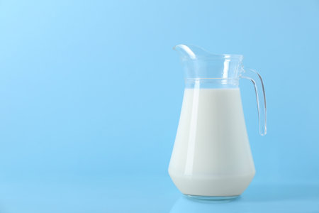 Jug of fresh milk on light blue background, space for textの写真素材