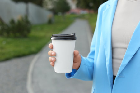 Coffee to go. Woman with paper cup of drink outdoors, closeupの写真素材