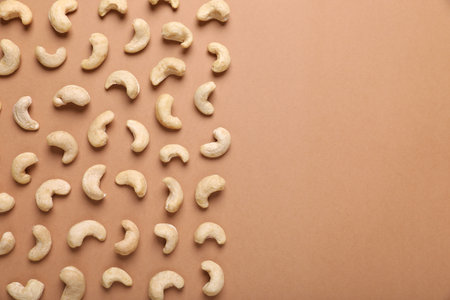 Many tasty cashew nuts on pale brown background, top view. Space for textの写真素材