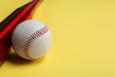 Baseball bat and ball on yellow background, closeup. Space for textの写真素材