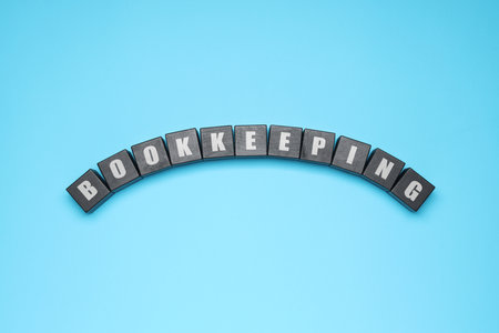 Word Bookkeeping made with black cubes on light blue background, top view