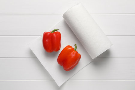 Roll of paper towels with bell peppers on white wooden table, top viewの写真素材