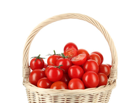 Wicker basket with fresh ripe cherry tomatoes isolated on whiteの写真素材
