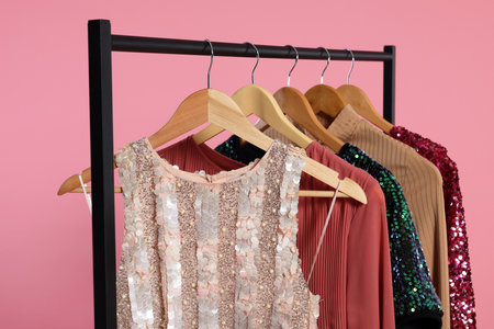Rack with stylish women's clothes on wooden hangers against pink backgroundの写真素材