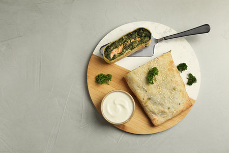 Delicious strudel with salmon and spinach served on light gray table, top view. Space for textの写真素材