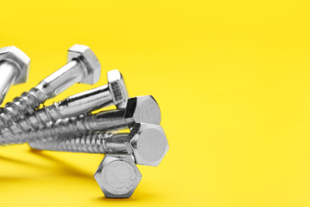 Many self-tapping screws on yellow background, closeup. Space for textの写真素材