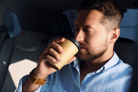 To-go drink. Handsome man drinking coffee in carの写真素材