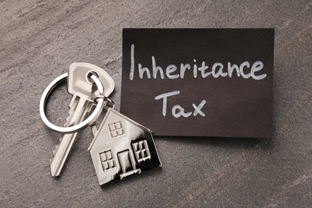 Inheritance Tax. Card and key with key chain in shape of house on gray table, top viewの写真素材