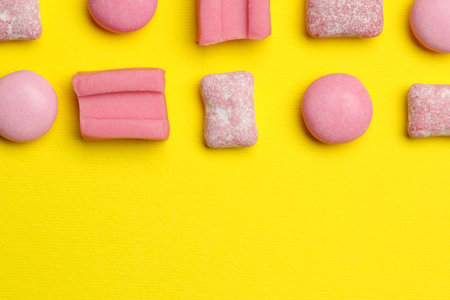 Pink bubble gums on yellow background, flat lay. Space for textの写真素材