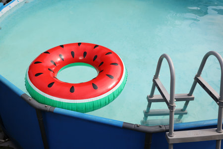 Inflatable ring floating on water in above ground swimming pool outdoors