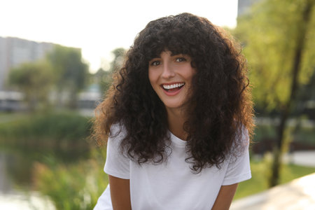 Portrait of beautiful woman posing outdoors. Attractive lady smiling and looking into camera