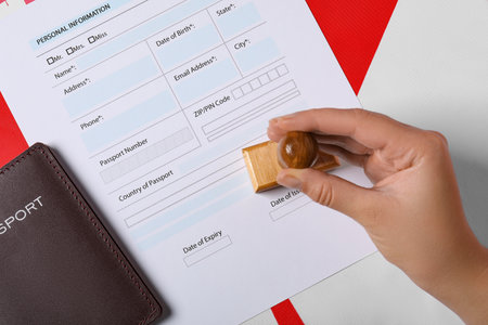 Immigration to Canada. Woman stamping visa application form on flag, top viewの写真素材
