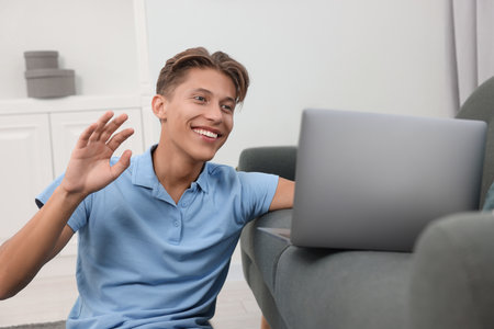 Happy young man having video chat via laptop indoorsの写真素材