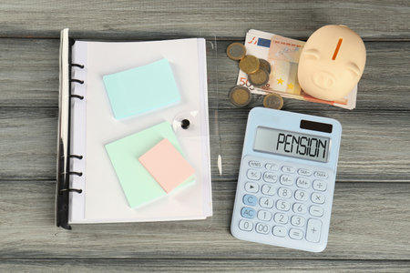 Calculator, piggy bank, euro banknotes, coins and folder on wooden table, above view. Pension planningの写真素材
