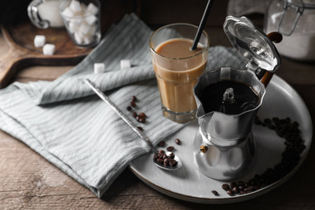 Brewed coffee in moka pot, glass of drink and beans on wooden table, space for textの写真素材