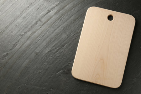 One wooden cutting board on dark gray table, top view. Space for textの写真素材