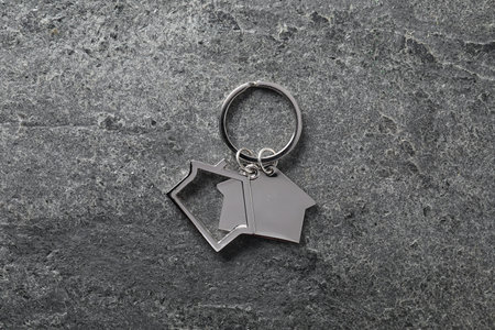 Metal keychain in shape of houses on gray textured table, top viewの写真素材