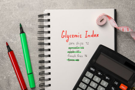 Glycemic Index. Notebook with information, markers, calculator and measuring tape on light gray table, flat layの写真素材