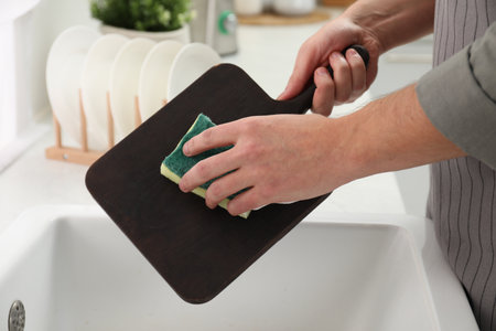 Man washing dark wooden cutting board at sink in kitchen, closeupの写真素材