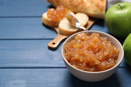 Bowl with delicious apple jam on blue wooden table, space for textの写真素材