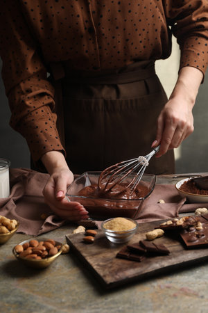 Woman mixing delicious chocolate cream with whiskey at gray textured table, closeupの写真素材