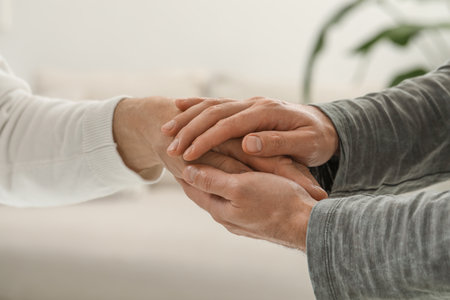 Trust and support. Men joining hands on blurred background, closeup