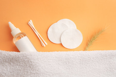 Flat lay composition with makeup remover, cotton pads and buds on pale orange backgroundの写真素材