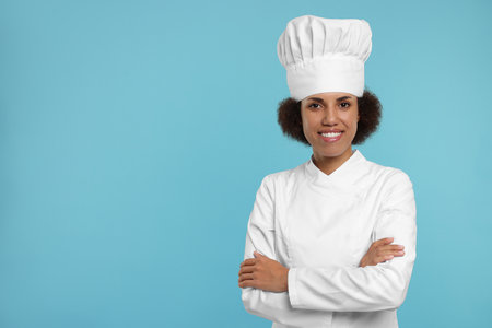 Portrait of happy female chef in uniform on light blue background. Space for textの写真素材