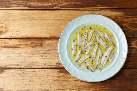 Tasty pickled anchovies with spices on wooden table, top view. Space for textの写真素材