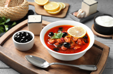 Meat Solyanka soup with sausages, olives and vegetables in bowl served on gray tableの写真素材