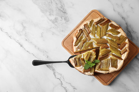 Freshly baked rhubarb pie with cake server on white marble table, top view. Space for textの写真素材